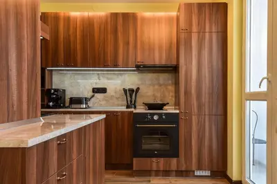 a kitchen with wooden cabinets and a black oven at Palace of Culture 2-Bedroom Retreat on Skobelev blvd in Sofia