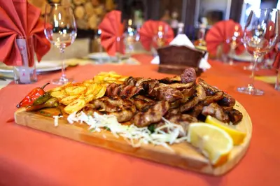 a plate of food with meat and vegetables on a table at Zlaten Rozhen Family Hotel- Monument of Cultural Significance in Rozhen