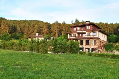 a large house on a hill in a field at Хотел Планински кът in Dorkovo