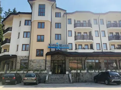 a large building with cars parked in front of it at Studio Villa Park Premium in Borovets