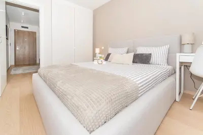 a white bedroom with a large bed and a desk at Plovdiv City Center Kapana with garage in Plovdiv