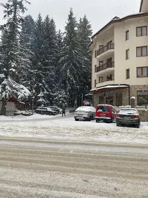 a snow covered street with cars parked next to a building at Studios -Villa Park SV in Borovets