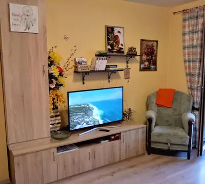 a living room with a flat screen tv and a chair at Апартамент Allegri Padrini Комплекс Вели Хилс in Velingrad