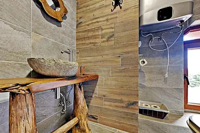 a bathroom with a stone sink on a wooden wall at Charming apartment in the heart of Bansko in Bansko