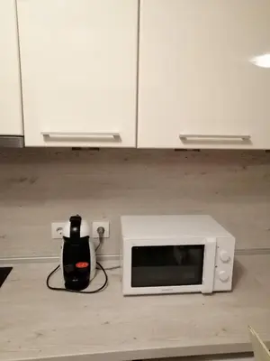 a white microwave sitting on a counter with a black object at Apartments in Borovets Gardens in Borovets