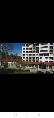 a large white apartment building with a parking lot at Apartments in Borovets Gardens in Borovets
