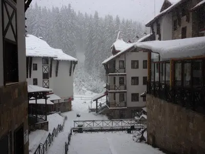 a snow covered town with buildings and trees at Ski Apartment in Castle Complex in Pamporovo