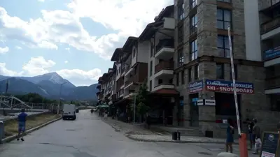 a street with a building and a van on the road at Apartman u kompleksu Royal Towers in Bansko