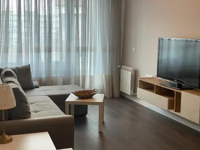 a living room with a couch and a flat screen tv at Apartment The Orchid in Sofia