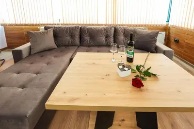 a couch with a wooden table with a bottle and glasses at Family Hotel Gotse Delchev in Gotse Delchev