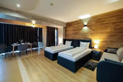 a hotel room with two beds and a table and chairs at Family Hotel Gotse Delchev in Gotse Delchev