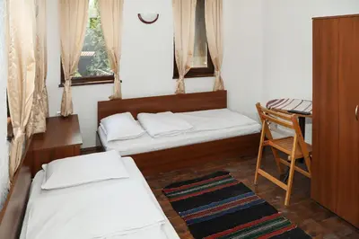 a room with two beds and a table and a chair at guest house Margarita in Bryagovo