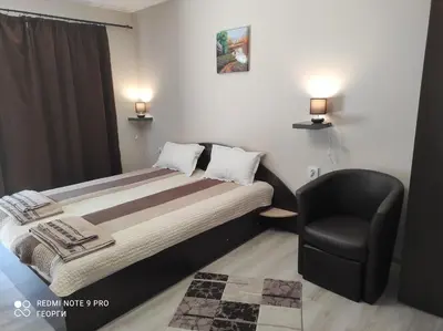 a bedroom with a bed and a black chair at Vila Rila in Sapareva Banya