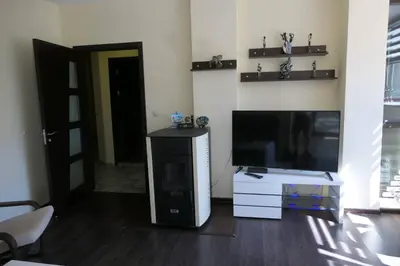 a living room with a flat screen tv and a desk at Апартамент Мия Deluxe in Velingrad