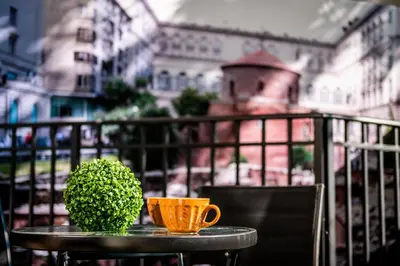 a table with a cup and a plant on a balcony at Sofia Rococo Life Apartments in Sofia