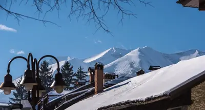 a snow covered roof with mountains in the background at NEXT TO GONDOLA. Cosy & Elegant 2 Bedroom apartment in Neon Complex in Bansko