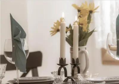 a table with two candles and a vase with flowers at Аpartment Gem in Centre of Sandanski in Sandanski