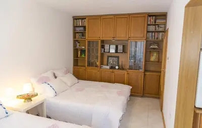 a bedroom with a white bed and wooden cabinets at Аpartment Gem in Centre of Sandanski in Sandanski