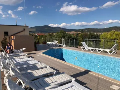 a woman sitting on a deck next to a swimming pool at Fantasy Apartment 15 комплекс Фантазия, Хисаря in Hisarya