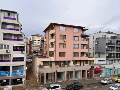 a tall pink building with cars parked in a parking lot at City View Apartment With 2 Bedrooms and Free Garage in Blagoevgrad