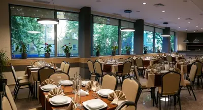 a dining room with tables and chairs and windows at Hotel Puldin COOP in Plovdiv