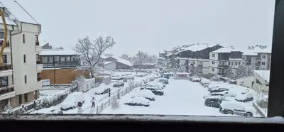 a city street covered in snow with cars parked at Lucy's Apartments Emerald in Bansko