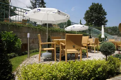 a group of chairs and tables with an umbrella at Family Hotel Diana in Sofia