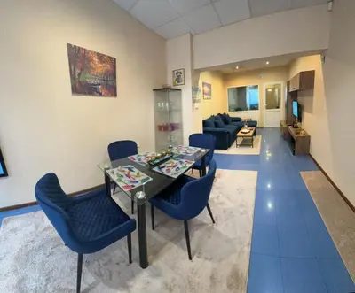 a living room with a dining table and blue chairs at KCT Downtown Apartment in Sofia