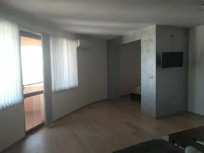 an empty living room with a television on a wall at Семеен Хотел Дани in Asenovgrad