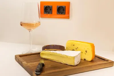 a wooden cutting board with cheese and a glass of wine at SCA Sofia City Apartments in Sofia