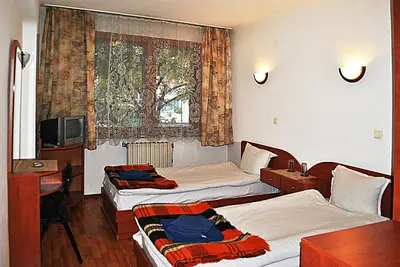 a hotel room with two beds and a desk and a window at Family hotel Zora in Sofia