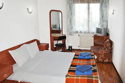 a bedroom with a large bed and a mirror at Family hotel Zora in Sofia