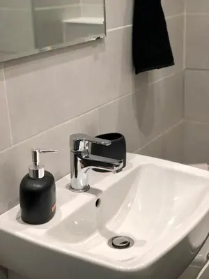 a bathroom sink with a black soap dispenser on it at Spacious modern vintage flat in the heart of Sofia in Sofia