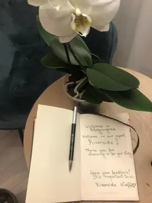 a notebook and a pen on a table with a flower at Riverside apart in Blagoevgrad