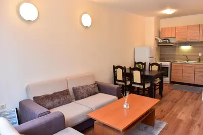a living room with a couch and a table and a kitchen at Cedar Lodge in Bansko