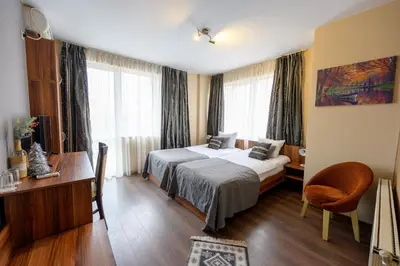 a hotel room with two beds and a desk at Ахат- къща за гости in Kyustendil
