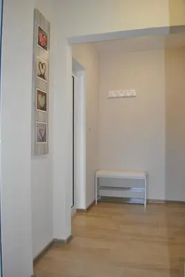 a room with a white wall with a bench and paintings at ComfortApartment IGLIKA 2 in Borovets