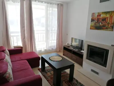 a living room with a red couch and a fireplace at Luxury apartments in St. John Park in Bansko