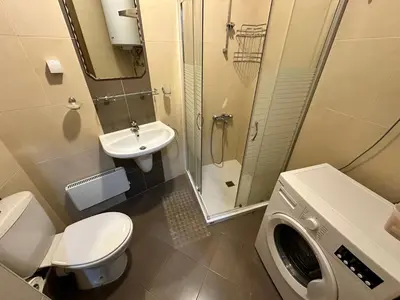 a bathroom with a toilet sink and a washing machine at Luxury apartments in St. John Park in Bansko