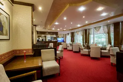 a waiting room with chairs and tables and a television at Хотел 