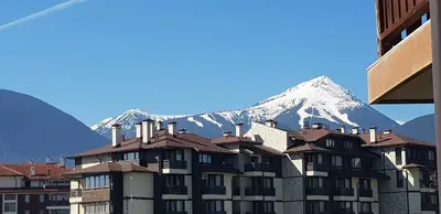 a building with a snow covered mountain in the background at Simon's studio in Bansko