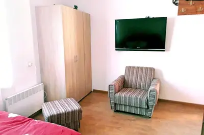 a bedroom with a tv and a chair and a bed at Нouse with cute little yard in Plovdiv