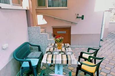 a table with chairs and a vase of flowers on it at Нouse with cute little yard in Plovdiv