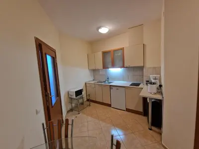 a kitchen with white cabinets and a glass table at Flora Apartments TMF in Borovets