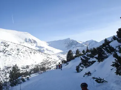a group of people skiing down a snow covered mountain at Flora Apartments TMF in Borovets