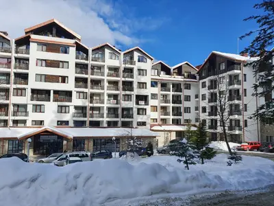 a large apartment building with snow in front of it at Borovets Gardens Apartments TMF in Borovets