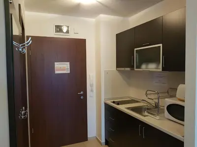 a kitchen with a door and a sink and a microwave at Borovets Gardens Apartments TMF in Borovets