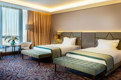 a hotel room with two beds and a chair at Grand Hotel Millennium Sofia in Sofia