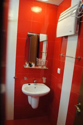 a red and white bathroom with a sink and a mirror at Бора Бора in Sapareva Banya