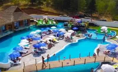 a pool with blue and white umbrellas and people on it at Бора Бора in Sapareva Banya